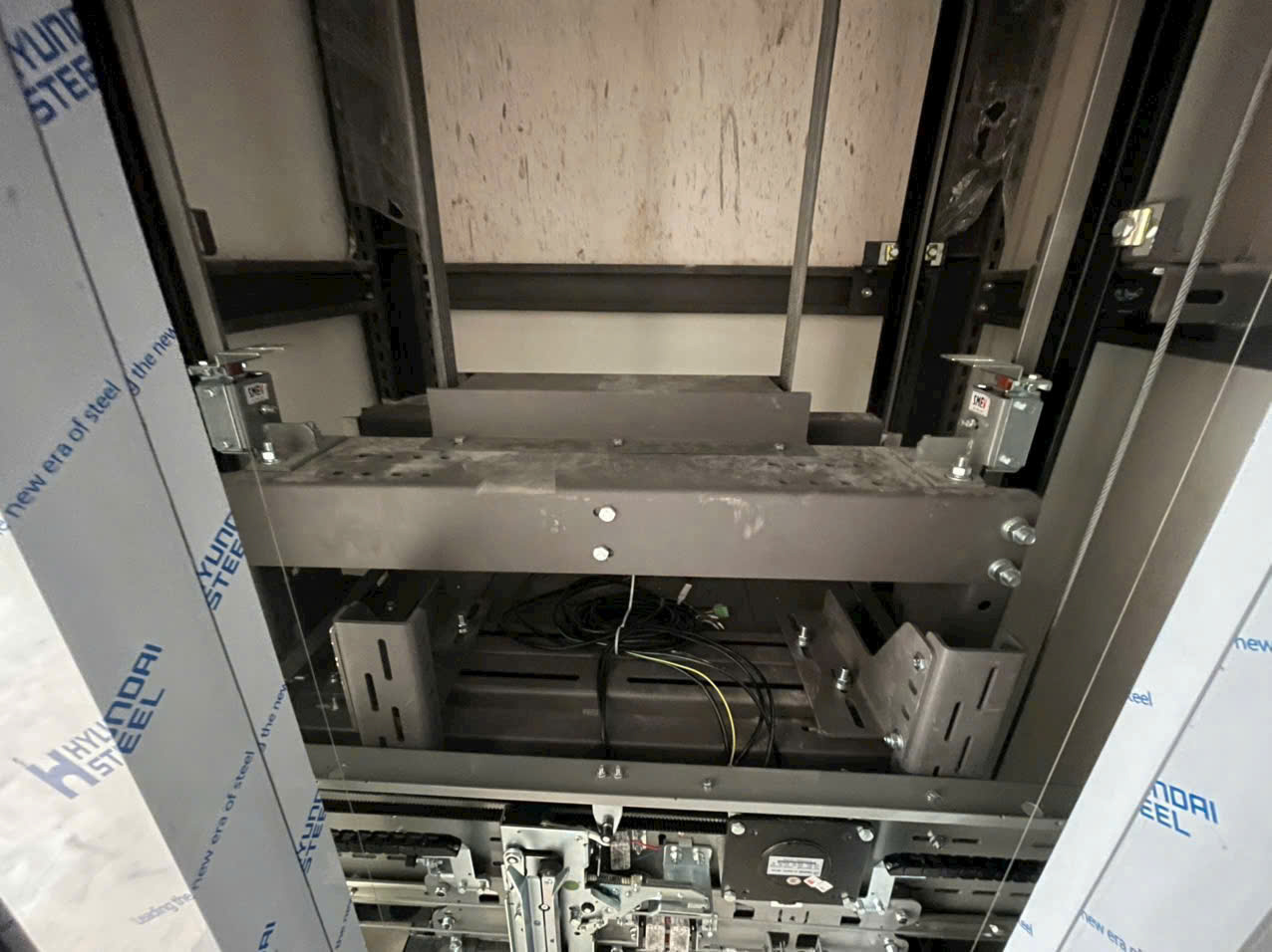 Hệ thống cơ khí và dây cáp trong hố thang máy đang lắp đặt bằng khung thép Hyundai Steel